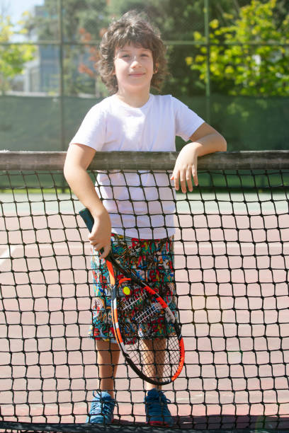 istock Happy boy playing tennis outdoors with a friend. 1396155633
