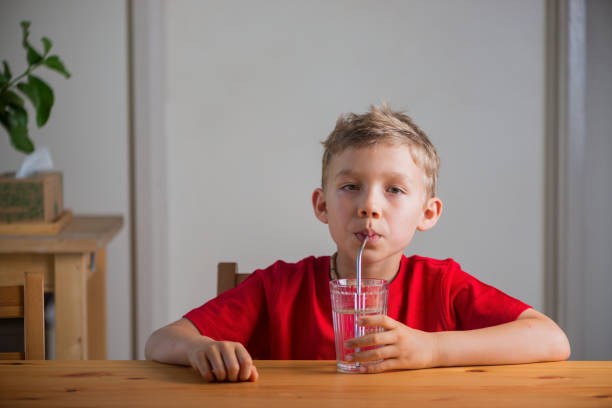 istock Cute boy drinking water through the drinking straw. Lifestyle portrait. 1396160730