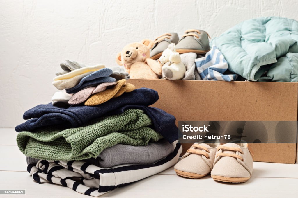 Baby and child clothes, toys in box. Second hand apparel idea. Circular fashion, donation, charity concept Clothing Stock Photo