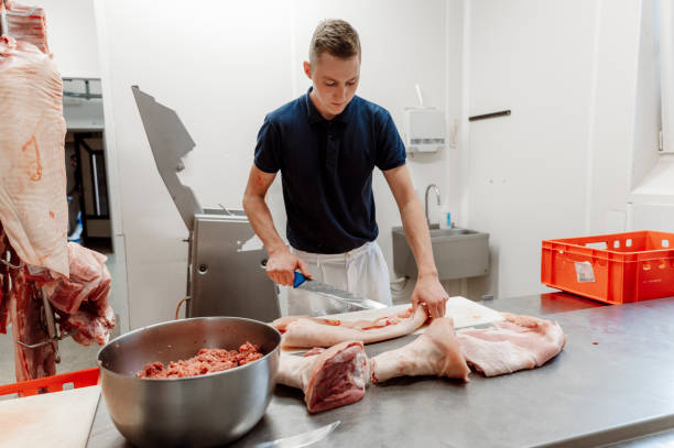 istock Young butcher cutting meat with a big knife 1396160919