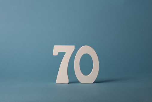 White wooden number seventy 70 on blue background. Copy space. Free space for your text and decorations. For birthday, anniversary, jubilee.