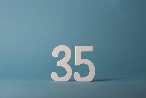 White wooden number thirty-five 35 on blue background. Copy space. Free space for your text and decorations. For birthday, anniversary, jubilee.