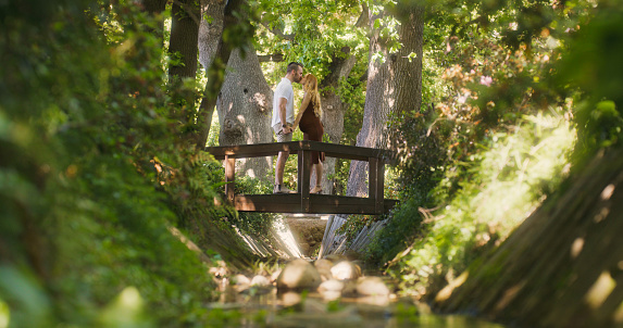 A pregnant young woman in nature with her husband, sharing a romantic moment. Happy couple enjoying a relaxing maternity leave outdoors