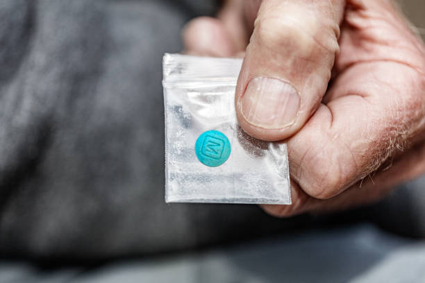 m 30 pastilla de fentanilo opiáceo en bolsa de plástico en primer plano de mano - fentanyl fotografías e imágenes de stock