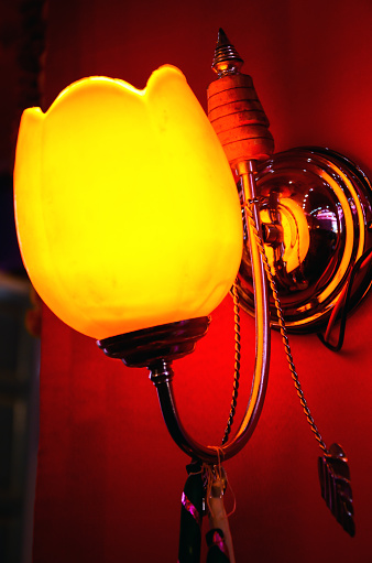 U curve hanging light on the wall. Yellow warm light bulb fixture lightening the darkroom. Luxury interior light for interior or exterior design