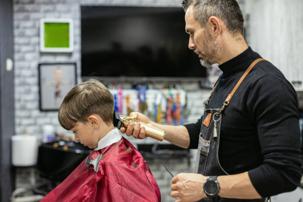 Cute boy getting haircut at hair salon stock photo
