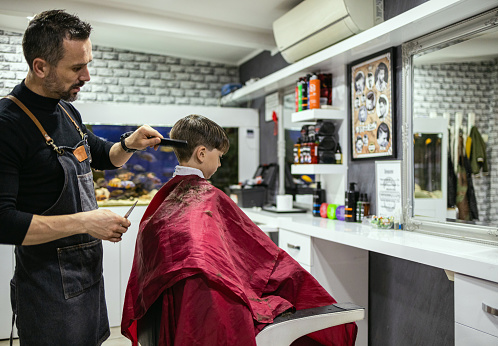 Little kid getting new haircut at the barber's shop