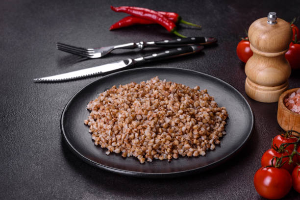 delicioso mingau de trigo cozido fresco com legumes e especiarias em um prato preto - buckwheat groats - fotografias e filmes do acervo