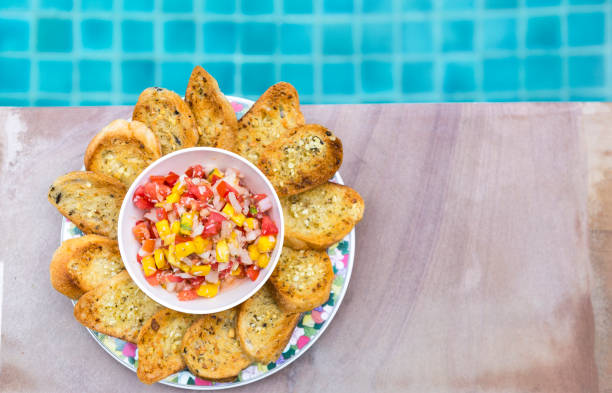 istock Homemade mango salsa with garlic bread with space on swimming pool edge background 1396194049