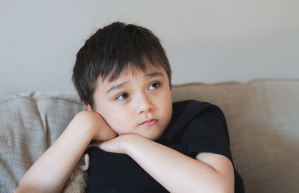 istock Portrait Young boy looking deep in thought, School Kid looking out with thinking face. Close up Child with curious face sitting alone on sofa. 1396194815