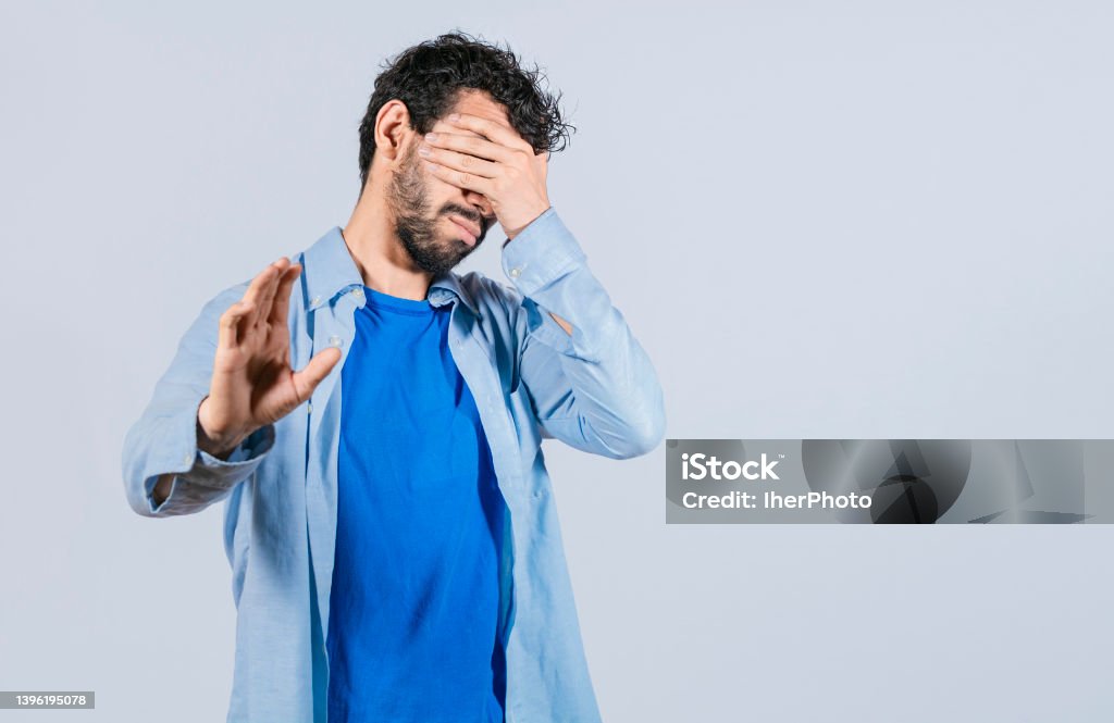 Scared confused man closing eyes with palm of hand Hiding Stock Photo