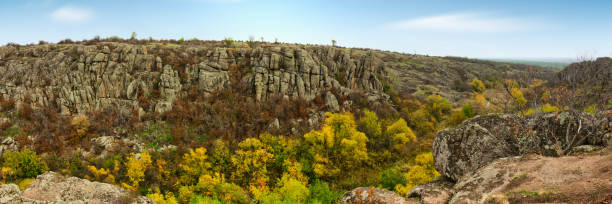 A large number of stone minerals covered with green vegetation lying above a small river in picturesque Ukraine and its beautiful nature A large number of stone minerals covered with green vegetation lying above a small river in picturesque Ukraine and its beautiful nature. High quality photo autumn field tree mountain stock pictures, royalty-free photos & images