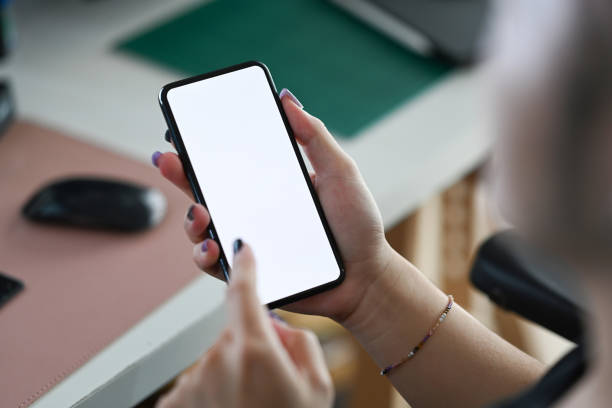 istock Over shoulder view stylish male using mobile phone while working at home office. 1396199683