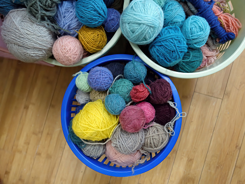 Colorful balls of yarn in the baskets on a wooden floor - top view