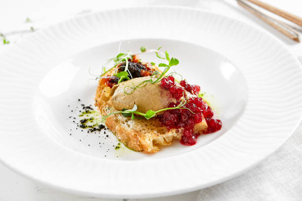 istock Chicken liver pate on crispy bread with red currant jam and micro green. Bruschetta with chicken pate in white plate. Delicious appetizer - foie gras on toast. Liver pate with jam in rustic style. 1396199896