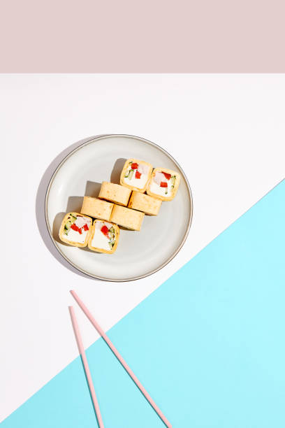 Mexican maki roll with chicken, paprika and cucumber inside, tortilla outside. Alternative sushi roll on coloured backdrop. Sushi menu concept. Maki sushi with chicken in minimal style