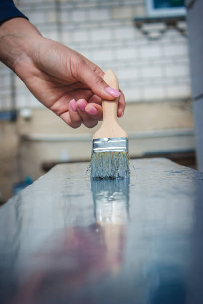 istock girl paints a board with a brush. Paint with gray paint. 1396202275