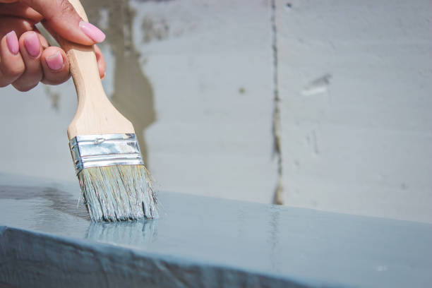 istock girl paints a board with a brush. Paint with gray paint. 1396202283