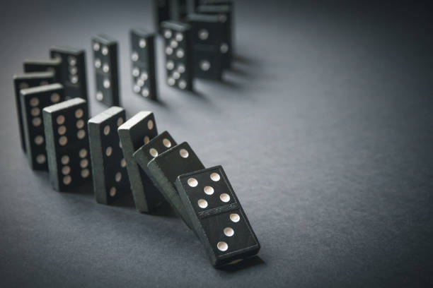 istock Black dominoes chain on dark table background 1396203301