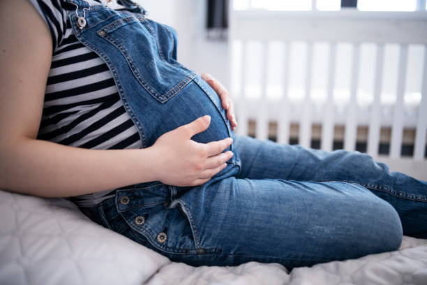 Heavily pregnant woman holding her bump. stock photo