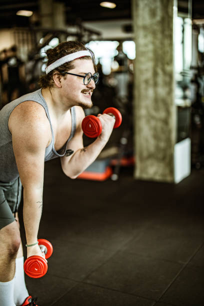 istock Funny athlete feeling determined while exercising with dumbbells in a gym. 1396207655