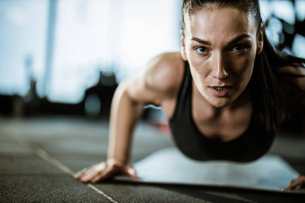 istock Determined athletic woman exercising push-ups in a gym. 1396207787