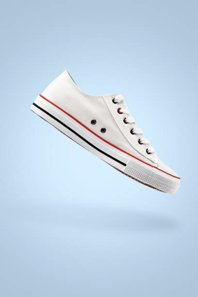 istock White female stylish sneakers on blue background 1396208536