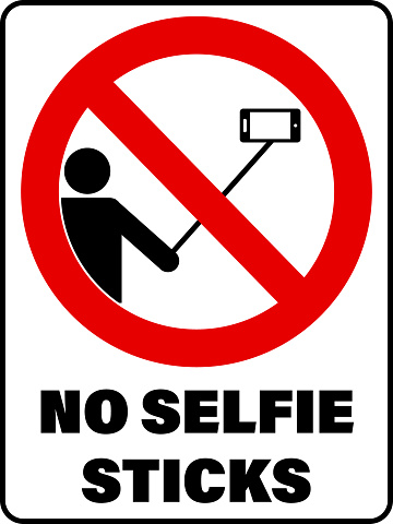 No selfie sticks, ban sign with a  person holding a selfie stick with a smartphone attached