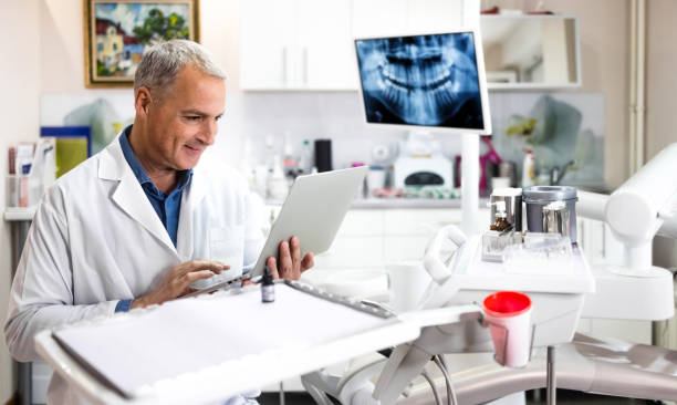 dentist doctor sitting at desk with laptop computer - dentist surgery dental hygiene using voice imagens e fotografias de stock
