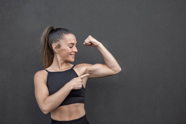 Muscular female athlete pointing at bicep short head biceps ripl fitness