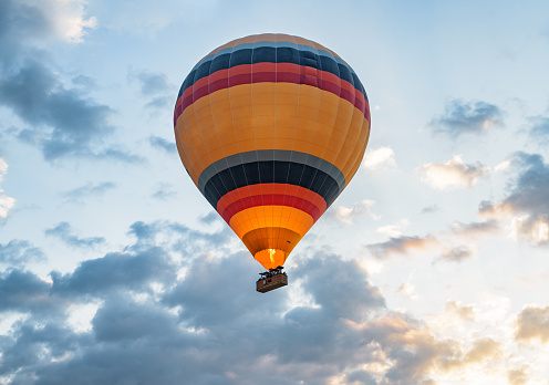 Closeup view of colorful hot air balloon on blue sky background at sunrise. The balloon is flying over Goreme Historical National Park, Cappadocia, Turkey. Cappadocia is a popular tourist destination.