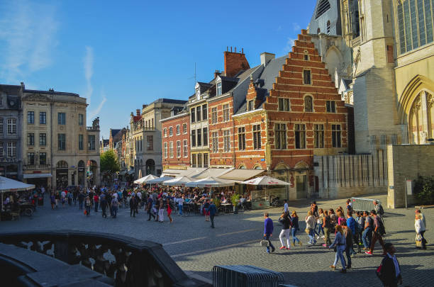 grote markt square en lovaina con grupos de personas caminando en un día soleado y casas típicas belgas - brussels waffle belgian waffle people fotografías e imágenes de stock