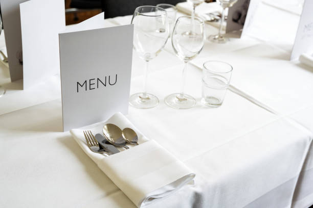 istock Elegant place setting with menu card, various glasses, cutlery and napkin on a table with white tablecloth for a festive dinner, copy space, selected focus 1396216773