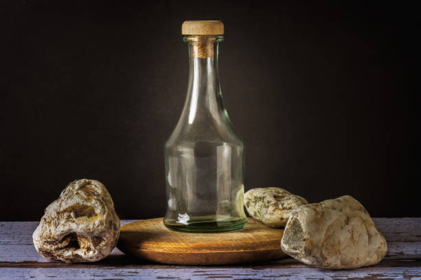 Still life antique bottle with stones on a wooden table with white and brown streaks and a black background.