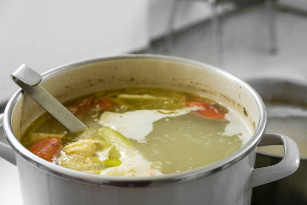 Vegetable soup - Creamy broccoli soup in pot, with dry fried pumpkin seed and piece of bread ready to eat, close up