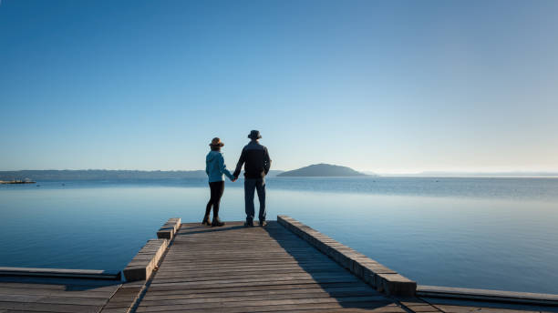istock Couple holding hands, standing on the lakefront boardwalk, Rotorua. 1396217793