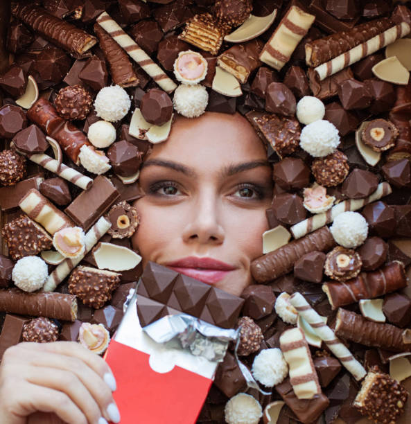 istock Beautiful woman dreaming while tasting eating enjoying chocolate bar on chocolate candy background 1396218031