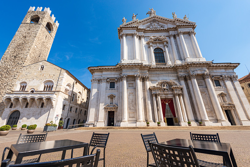 Brescia, Italy - April 17, 2022: Brescia downtown. Cathedral of Santa Maria Assunta,1604-1825, in late Baroque style, also called Duomo nuovo (New Cathedral), and Medieval Broletto Palace (Palazzo Broletto), XII-XXI century, with the ancient tower (Torre del Popolo o del Pegol) and the Loggia of Cries (Loggia delle Grida). Cathedral square or Paolo VI square. Lombardy, Italy, Europe.