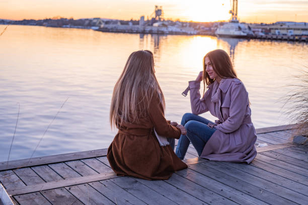 istock Two female friends sitting on the pier and talking 1396219644