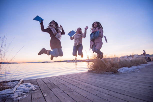 istock Young female students having fun jumping by the river 1396220257