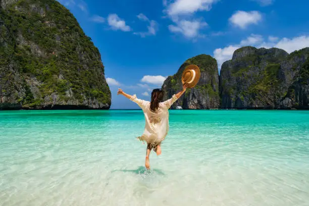 Young woman traveler relaxing and enjoying at beautiful tropical white sand beach at Maya bay in Krabi, Thailand, Summer vacation and Travel concept