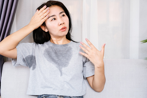 Asian woman sweating because of hot weather, menopause symptom concept