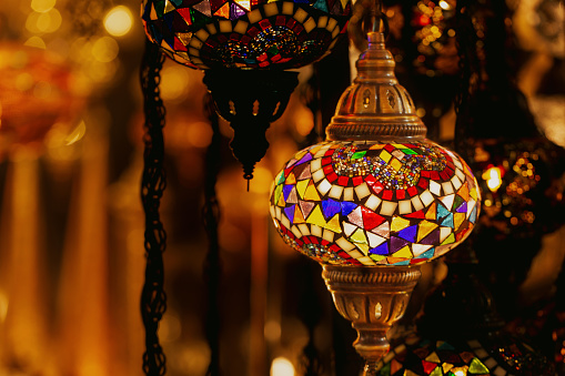 Traditional turkish or moroccan light mosaic lamp. Colorful stained glass lamp against defocused souvenir shop background with copy space. Popular souvenir and ideas for present