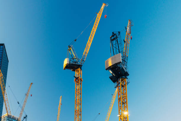 istock Cranes high up against blue sky in financial district, construction site by office buildings 1396228570