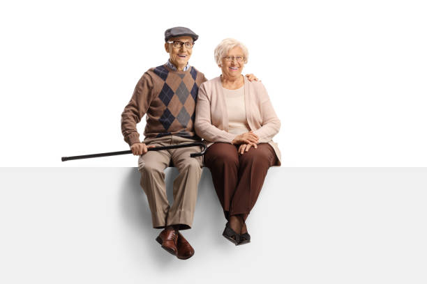 portrait en pied d’un couple de personnes âgées assis sur un panneau vierge et souriant à la caméra - senior couple grandparent cheerful happiness photos et images de collection