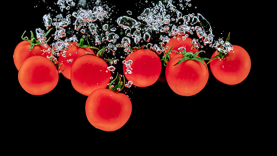 Close-up of cherry tomatoes in water against black background.