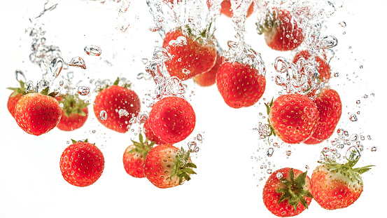 Close-up of strawberries in water against white background.