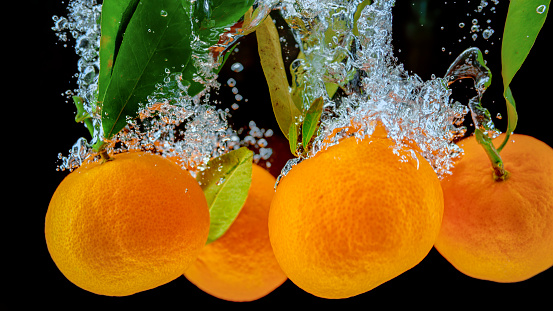 Close-up of oranges in water against black background.