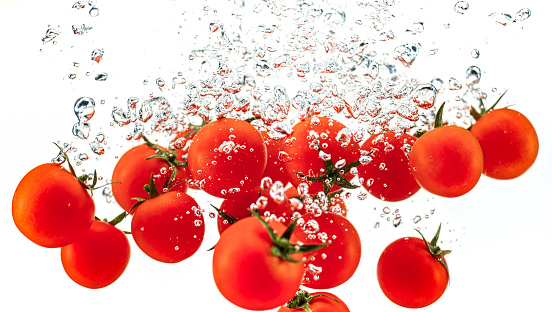 Close-up of cherry tomatoes in water against white background.