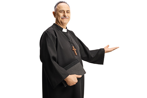 Mature priest gesturing welcome and holding a bible isolated on white background